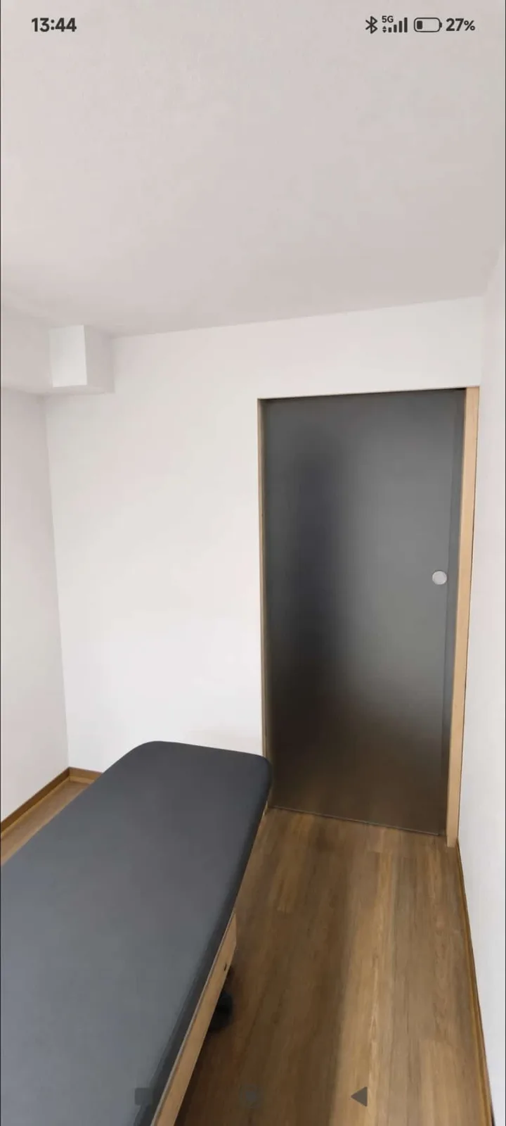 Renovierter Flur mit weißer Wand und dunkler Tür